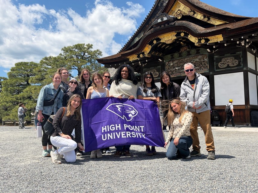 HPU students holding a High Point University flag outside Nijo Castle in Japan