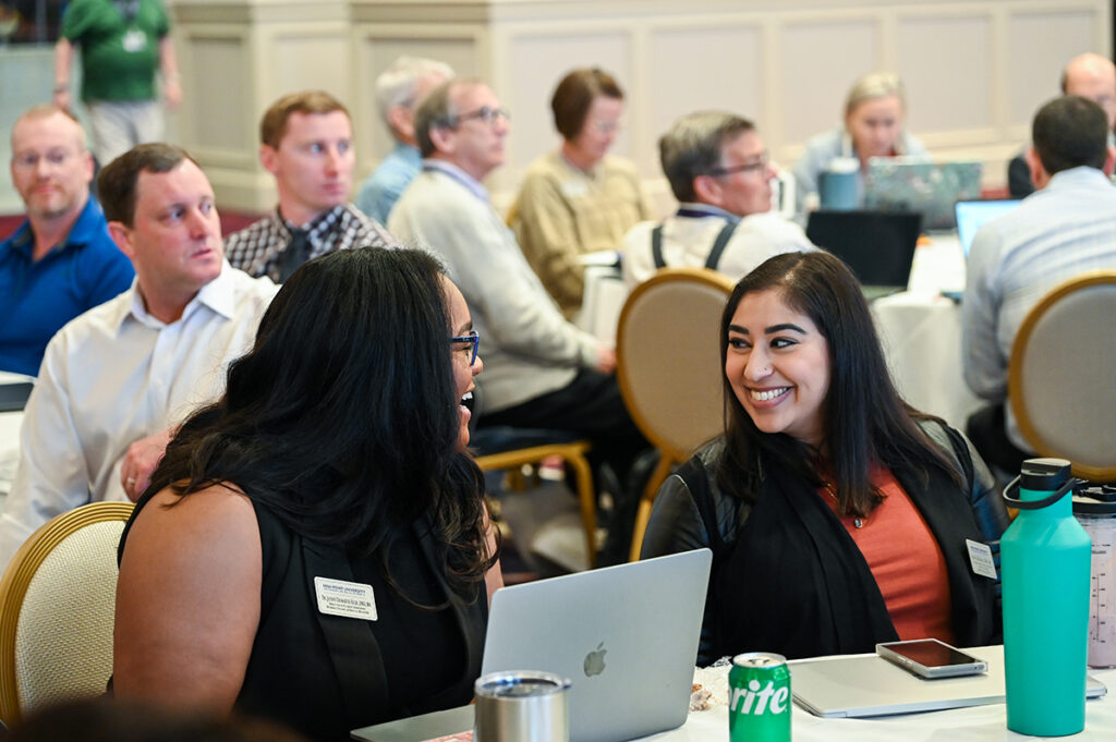 Two HPU faculty members smiled as they sat next to each other during the faculty seminar led by Echols in August.