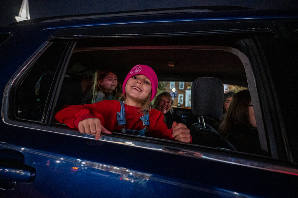 A female child smiles as she look out her car window at Christmas decorations on High Point University's campus.