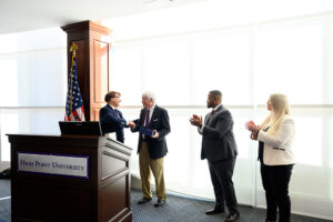 Mark Martin, the founding dean of the Kenneth F. Kahn School of Law, presented Hecht with the school’s inaugural Lawyer in the Arena Award at the luncheon on Jan. 8. Pictured from left is Martin as he handed Hecht the award as High Point Mayor Cyril Jefferson and Rebecca Costello, president of the High Point Bar Association, clapped.