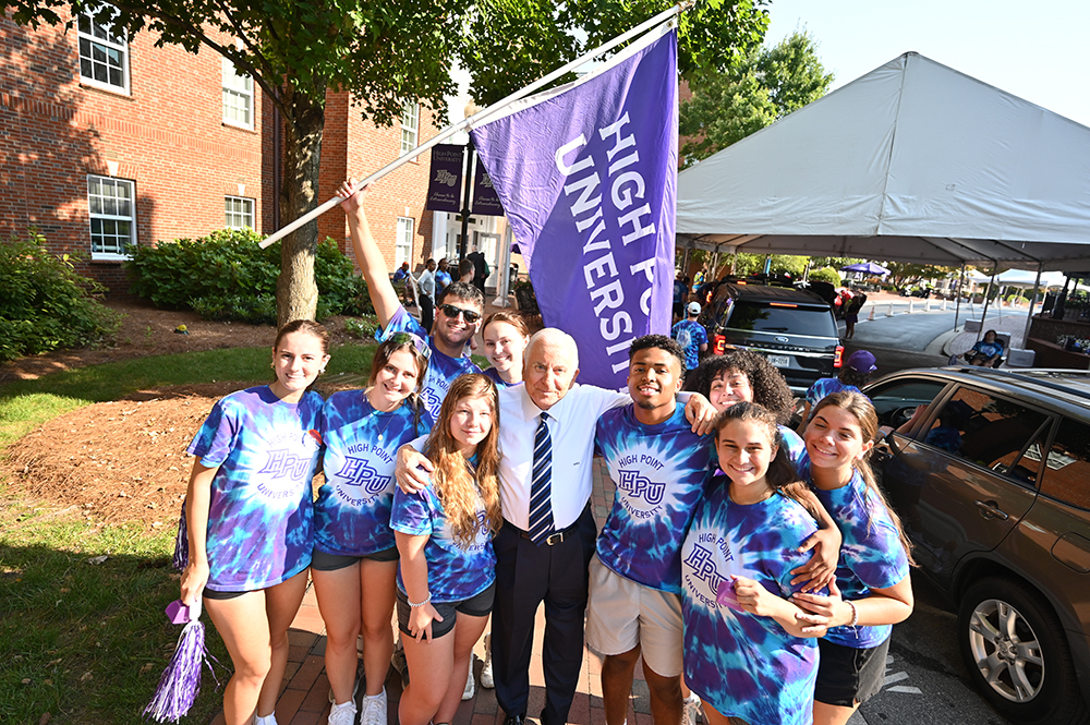 High Point University President Nido Qubein poses for a photograph with HPU students in tie-dyed shirts during Move-In Weekend in 2024.