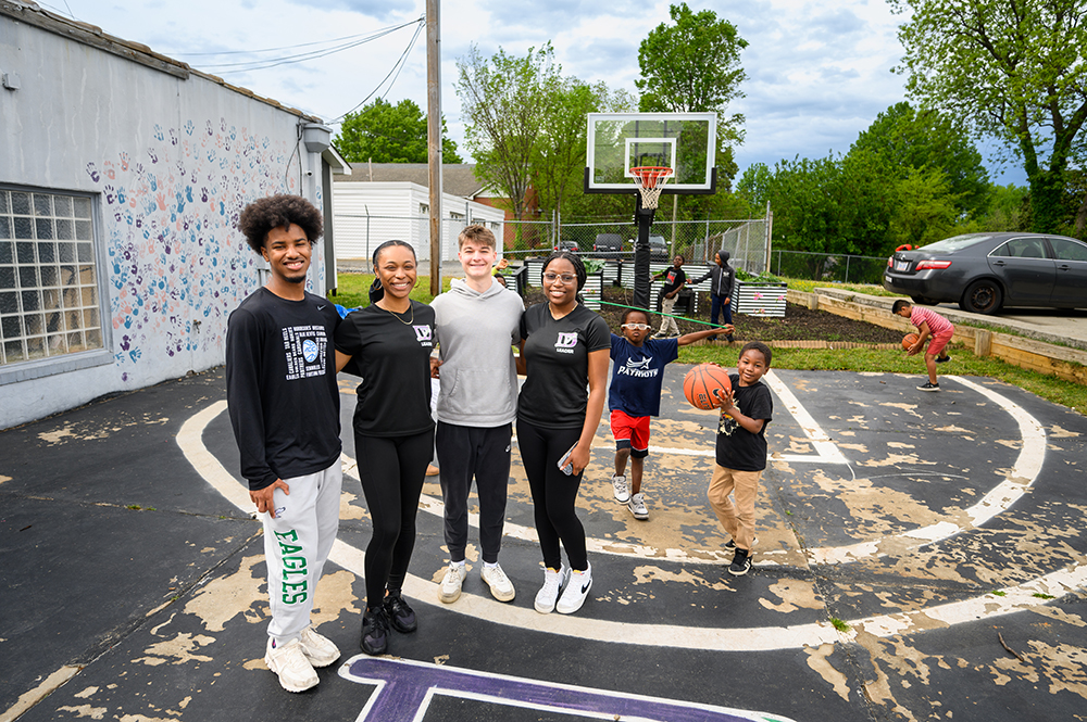 A group of High Point University Bonner Leaders and AmeriCorps VISTAs pose for a photograph on the basketball court at D-Up, a nonprofit in the city of High Point.