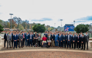 As part of their annual Operation K.A.R.E. initiative, HPU's Kappa Alpha Order fraternity raised $104,000 this year to donate four track chairs to critically injured veterans to improve mobility. Two of the Track Chairs were donated to veterans at today's event through The Independence Fund. Pictured are fraternity brothers with the veterans who received the chairs. In the front center row from left to right are Track Chair recipients Sgt. Cory Jason Muzzy, wife Beth Muzzy, Sgt. James Stanley King and wife Beth King.