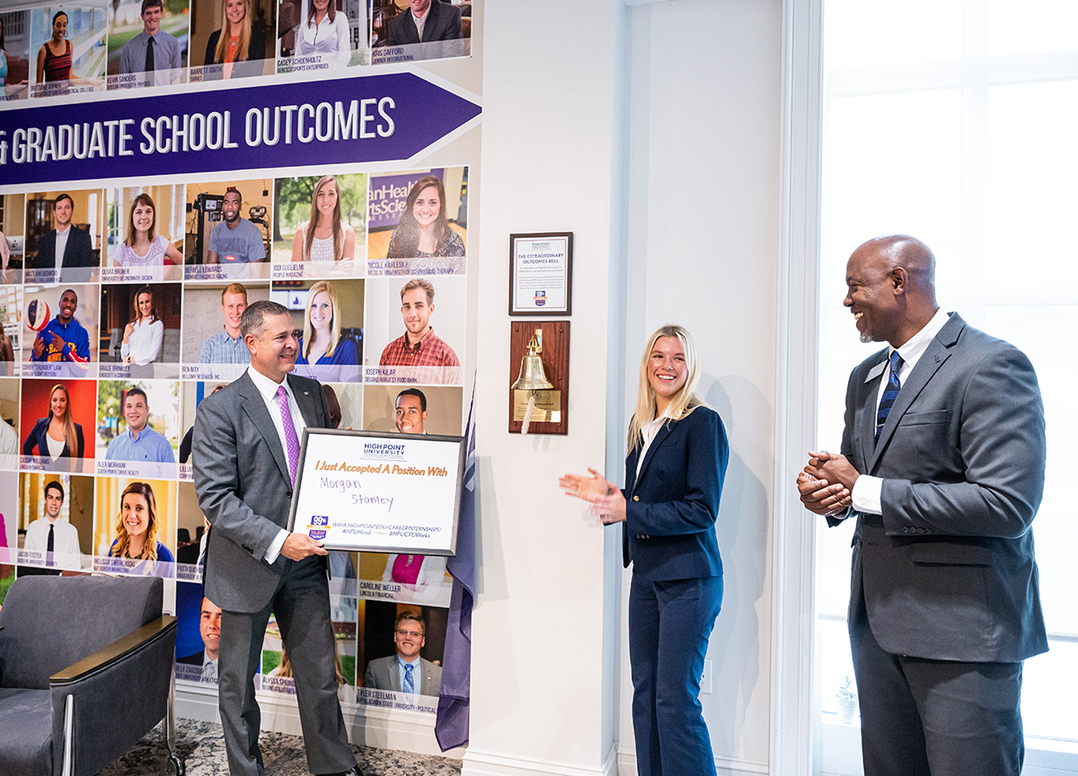 ) Bradburn held a sign indicating Lily Nelson, the first HPU student to ring the newly installed Extraordinary Outcomes bell in HPU’s Office of Career and Professional Development, had accepted a position with Morgan Stanley. Nelson received support from Dr. Doug Hall (right), vice president of Career and Professional Development.