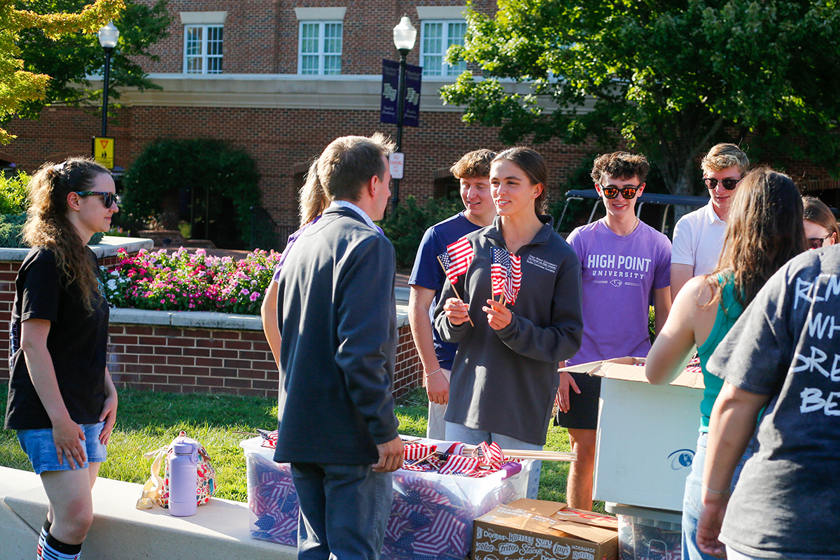 At center, Caitlin Black, a freshman computer science major from High Point, talked with HPU Student Government Association President Benjamin Niehaus as students started the flag planting at Patriots Plaza. Behind them from left are Taylor Cox, a communications and business leadership graduate student from Laurel Springs, North Carolina; Alex Muravski, a freshman mechatronics engineering major from Tulsa, Oklahoma; Asher Wimberly, a freshman business administration and biology major from Pinehurst, North Carolina; and William Briden, a freshman international business major from Batavia, Illinois.