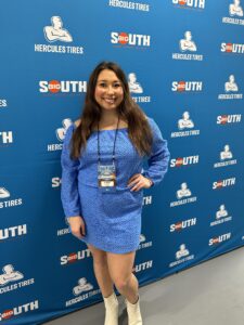 Reagan Smith standing in front of a blue background that says Big South Conference on it.