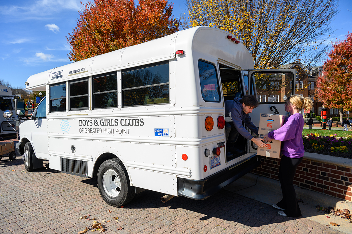 Regan Stillman, a senior finance and marketing major from Linwood, New Jersey, passed two boxes filled with Thanksgiving meals to Mark Black, assistant property and safety director of the Boys and Girls Club of Greater High Point to load into a bus.