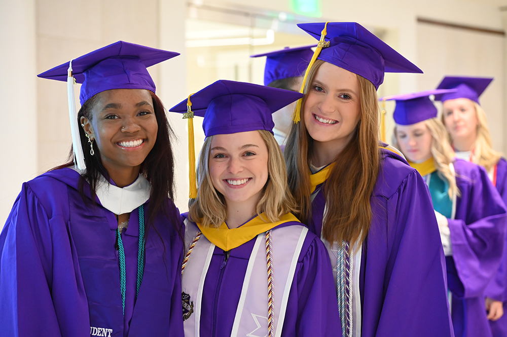 Three graduates smiled as they lined up before heading into the conference center.