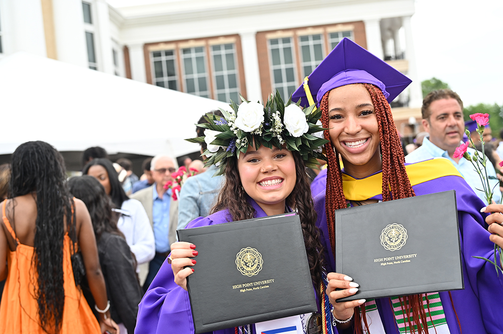 Two HPU graduates smiled as they posed with their diplomas outside the arena following their Commencement ceremony.