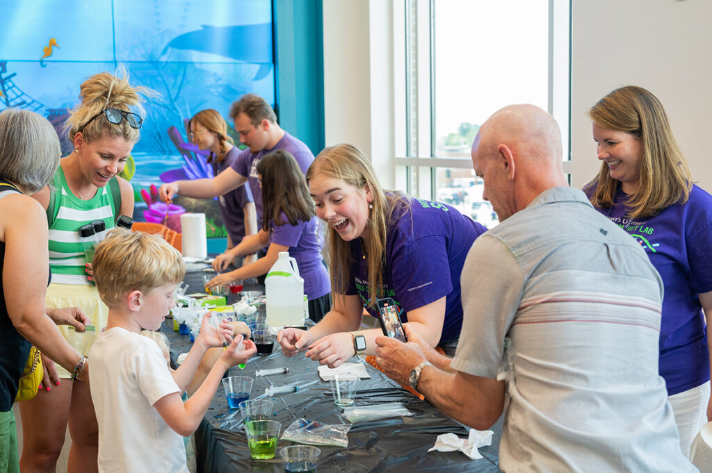Chloe Cox, a recent HPU alumna who is pursuing her doctorate in medicinal chemistry, interacted with a boy playing with goo worms under the observation of his parents and Dr. Meghan Blackledge, director of HPU’s Natural Science Fellows and associate professor of chemistry.