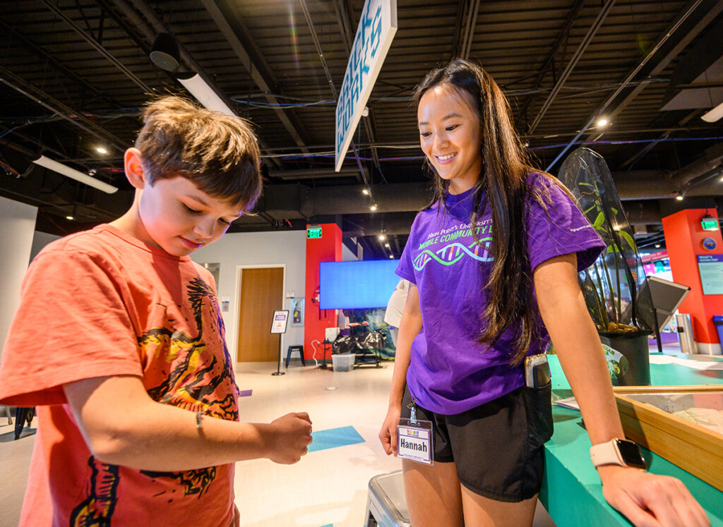A boy let a caterpillar climb on his arm in the insect petting display as HPU student Hannah Stewart observed.
