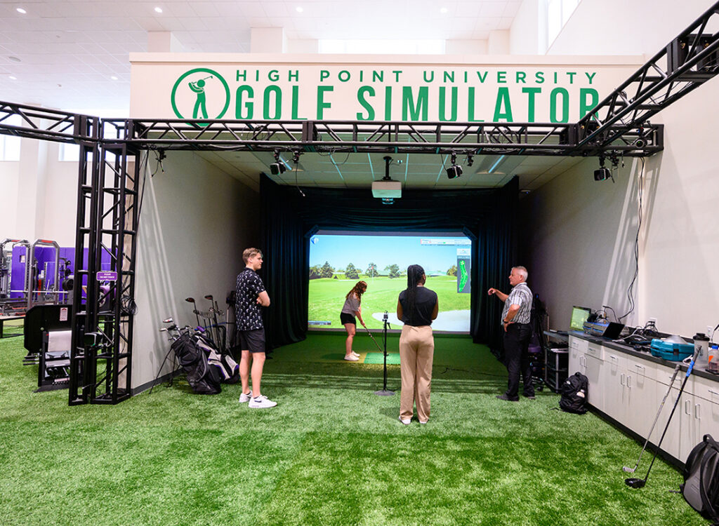 Westyn Woodard, left, observes Abby Capps’ golf swing in the HPU Golf Simulator, with Kennady Milligan and Dr. Don Goss.