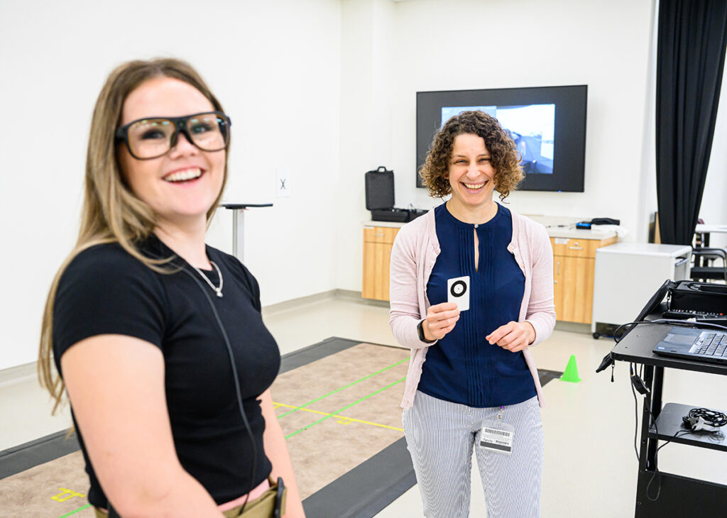 Phoenix Ward, a sophomore exercise science major, demonstrates eye-tracking goggles used this summer in HPU’s Virtual Reality and Gait Analysis Lab with Dr. Lisa Zukowski, associate professor of physical therapy, holding the focus circle target for research subjects.