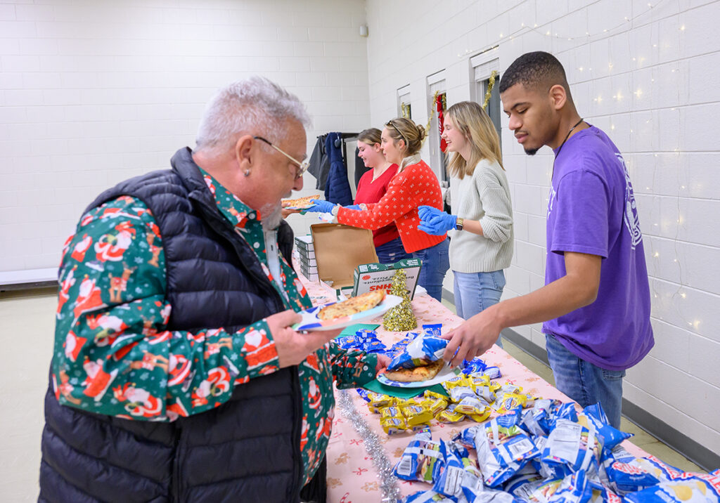 At right, Devin Townsend, a freshman elementary education major from Canton, Massachusetts, handed a bag of potato chips to a community member. Other HPU CEC members Larissa Paddock, Allison Currie and Katherine Shaw provided pizza.