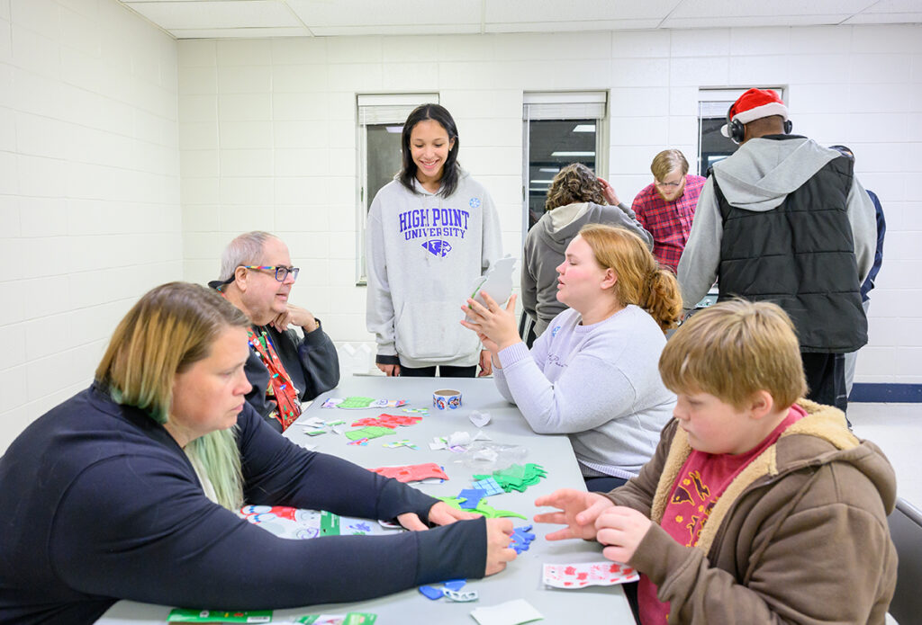 HPU students Victoria Robinson, pictured standing at center, and Lanie Jordan, pictured to her right, helped community members make holiday crafts.