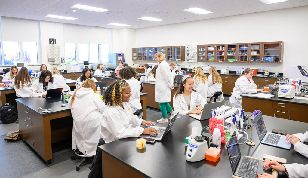 Dr. Dinene Carter is pictured at center working with freshmen who are researching in a lab.