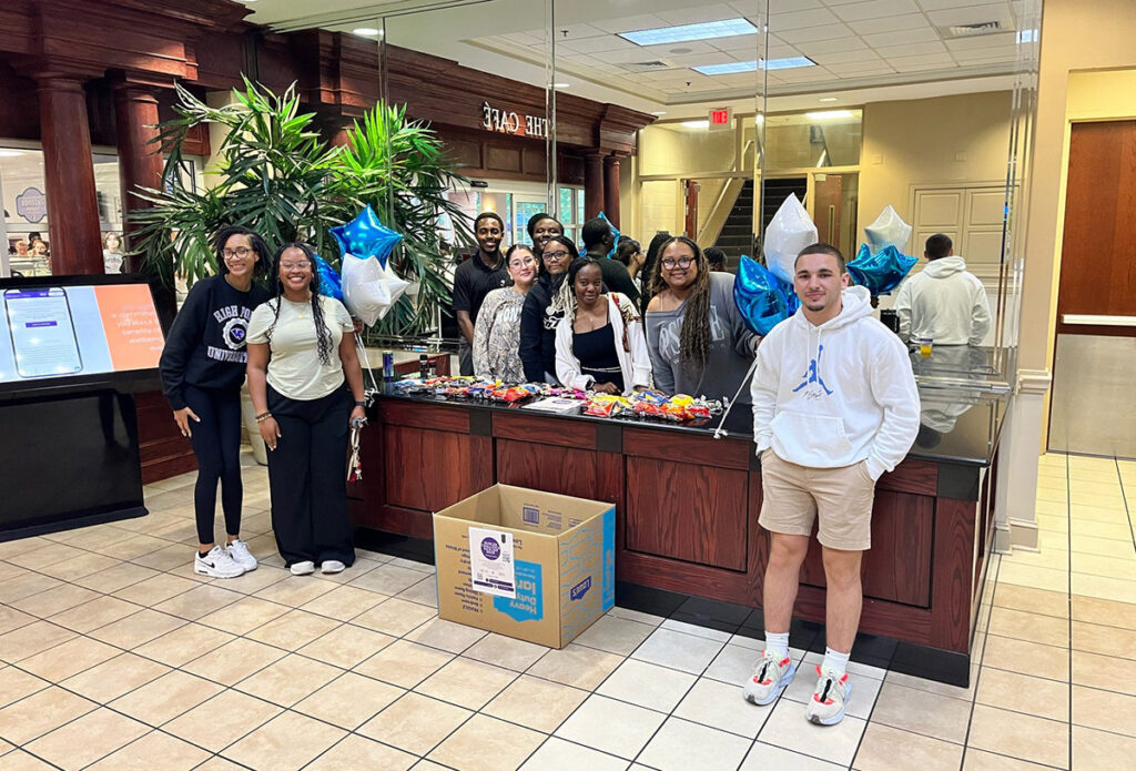 HPU Volunteer Center Executive Council members helped host the Hunger Challenge Bash as a kickoff to get students excited about the challenge and educate them about additional events. Pictured from left at the Slane Student Center Philanthropy Tables, where students could contribute nonperishable food, were council members including Hunger Challenge Ambassador Tenisha Cherenfant, Indya Spears, Dillon Pickney, Gayden Hill, Angelica Bajenoff, Hunger Challenge Ambassador Kay Gattison, Treasure Brown, Mae Culbreth and Jack Migdal Green. 