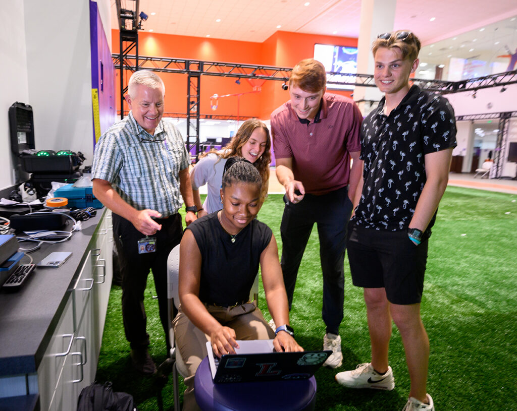 Kennady Milligan, an exercise science major, is seated as she analyzes golf swings on a computer. Behind her from left are Dr. Don Goss, associate professor of physical therapy; Abby Capps, a physical therapy student; Zach Swift, a Class of 2026 doctor of physical therapy candidate; and Westyn Woodard, a biology major.