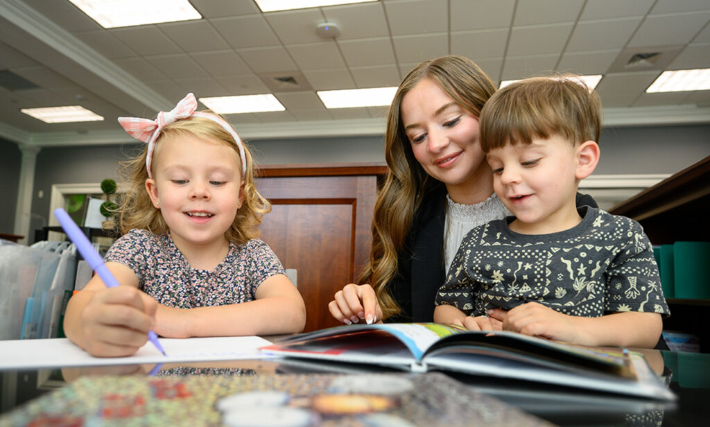 Gallagher smiled as she worked with two children in Gallagher in the Stout School of Education children’s library.
