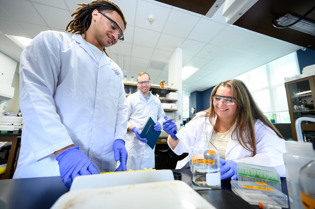 High Point University student Philip Morisseau, left, and Dr. Jeremy Whitson, assistant professor of biology, observed as Angelina Roy filled a pipet as part of their research on age-related cataracts.