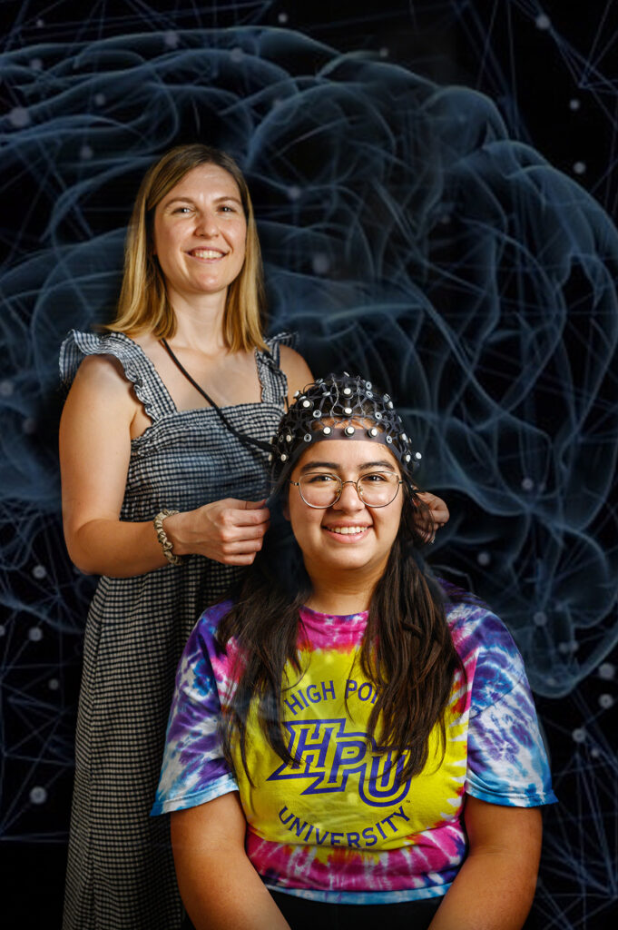 Dr. Kelsey Sundby, assistant professor of psychology, adjusted a skull cap on Violet Ruiz Sanchez, a sophomore psychology major who researched the vulnerability of memory.