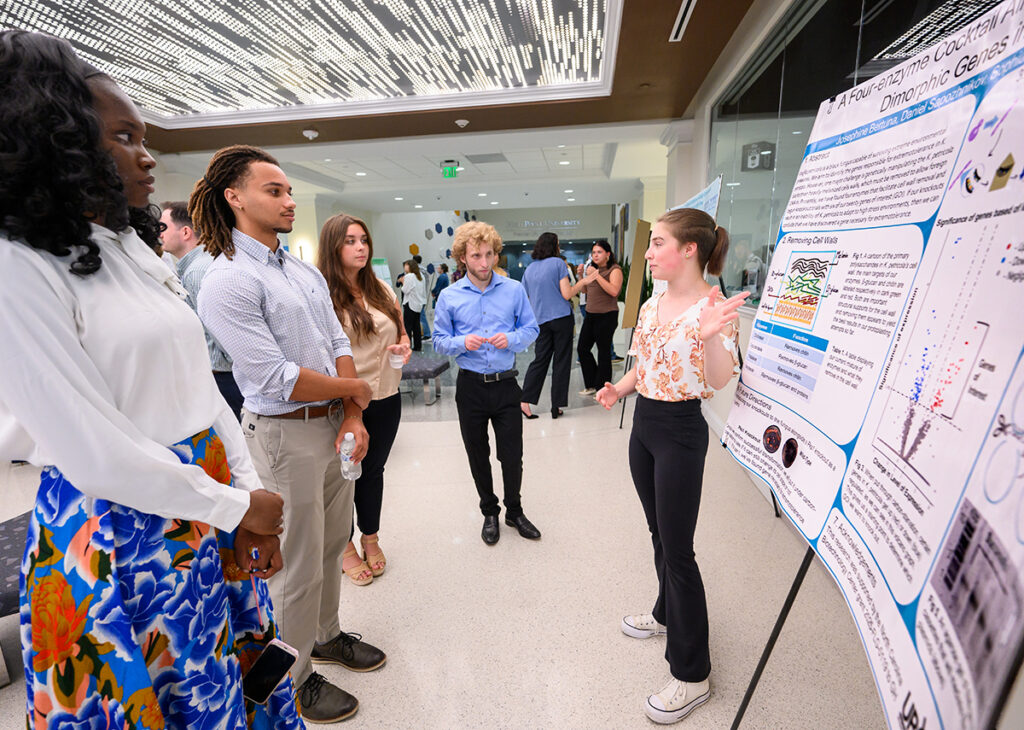 ) Josephine Bertuna, a sophomore biology major, talked with other students about her research poster detailing a black fungus capable of surviving extreme temperatures. She gave her presentation in the lobby of the Wanek School of Natural Sciences.