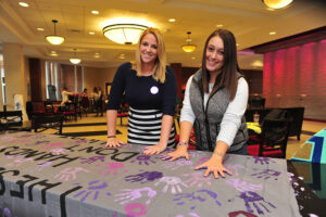HPU students Caroline Logan (left) and Jenn Silva (right) take a pledge to raise awareness about domestic violence at the “These Hands Don’t Hurt” event.
