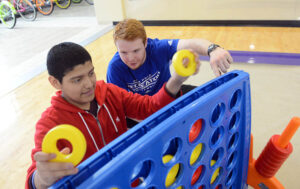 The photo features Southwest Middle School student Brian Cedeno and HPU student Jack Swartz playing Connect Four.
