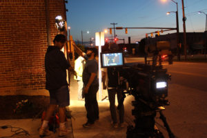 Ben Farmer, center, and other students from the Senior Production Experience class adjust the lighting during a film shoot.