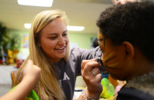 Junior Lexi Valentinas paints tiger whiskers on a student’s face. 