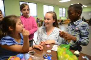 Freshman Whitney Bosserman helps children sort through the Easter egg candy they found. 