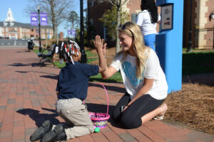 The photo features Tatiana Matthews (left) and Chloe Young (right) congratulating Matthews for the eggs she found at the Easter egg hunt.