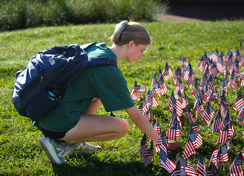 An HPU student pauses between her classes to add another flag to the display at Patriots Plaza.
