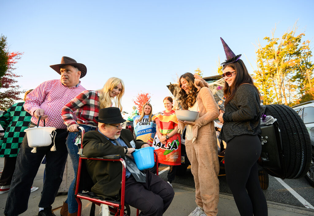 HPU students Kristina Parimucha, second from right and dressed as Scooby Doo, and Julie Bugg, at far right dressed as a witch, smile as they offer treats to trick or treaters at the Halloween special populations event.