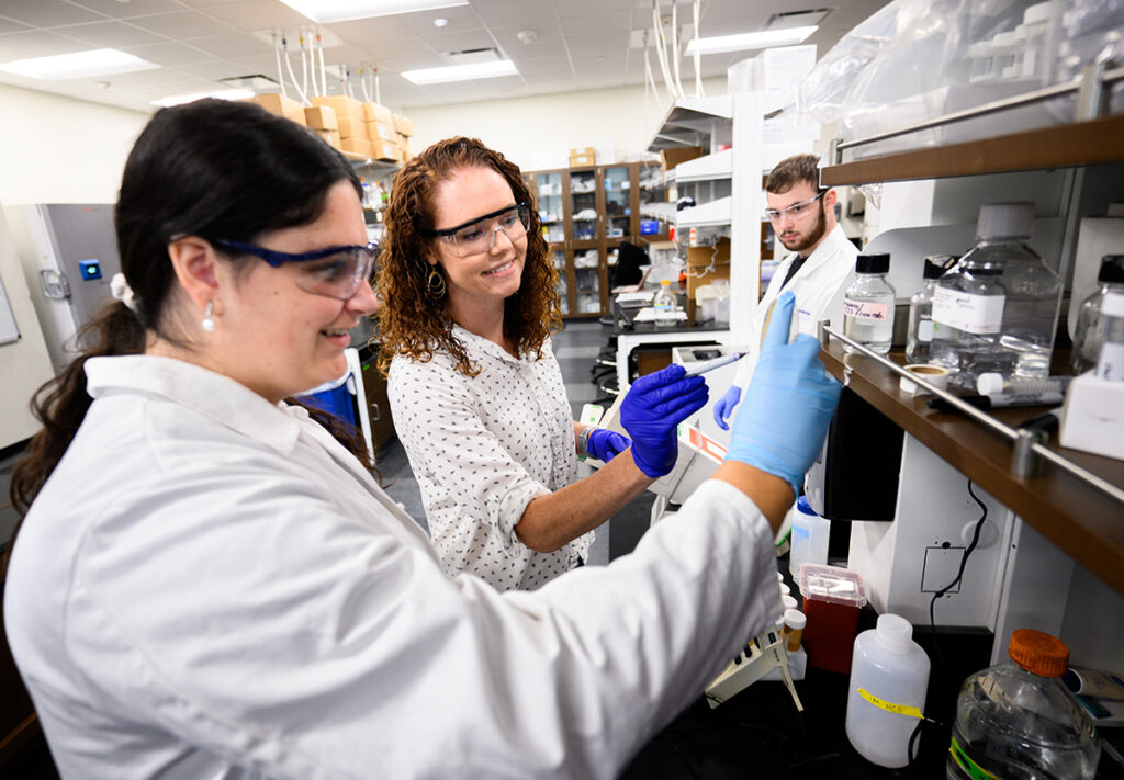 Master’s student Tori Federico, left, works in the lab with Dr. Heather Miller, associate professor of biochemistry, and Gabe Valenzano on project to overcome antibiotic resistant bacteria.