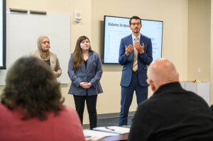 Three HPU pharmacy students giving a presentation.