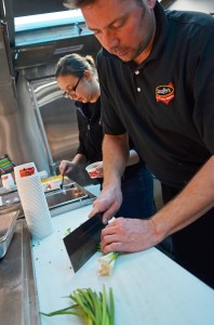 Stouffer’s employee Jae Stulock (right) chops scallions while Sandy Matachik tops off a cup of mac and cheese with bacon.