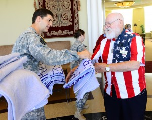 Student John Clemmer offers the gift of a blanket to veteran Leon McKusick.