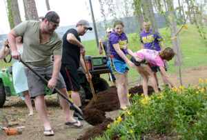The photo features Lee Brice with HPU students planting flowers.