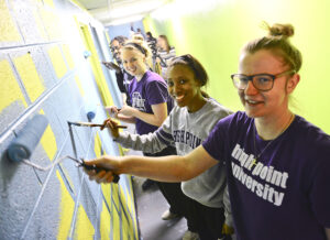 From right to left, Teddy Vincent, Ashante Richard and Maja Michalska, all members of HPU’s women’s basketball team, paint the interior of West End Ministries.