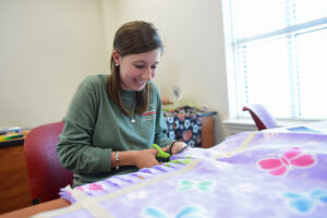 Jordan Herring cuts strips to tie her blanket’s fabrics together. 