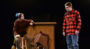 The photo features Roxanne Daneman (left) and Jake McDowell (right) in the play “Storm Warnings,” written by David Mikulay.
