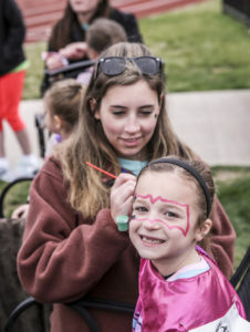 HPU student Ariana Baio face paints community member Blake Burick at the Super Hero Dash.