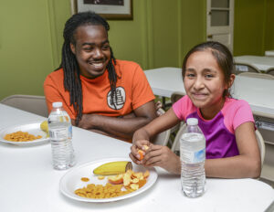  Kirkman Park Elementary School student Lizeth Cruz-Ruiz (right) enjoys a snack with HPU student and Bonner Leader Dante Armstrong (left) at the Community Writing Center. 