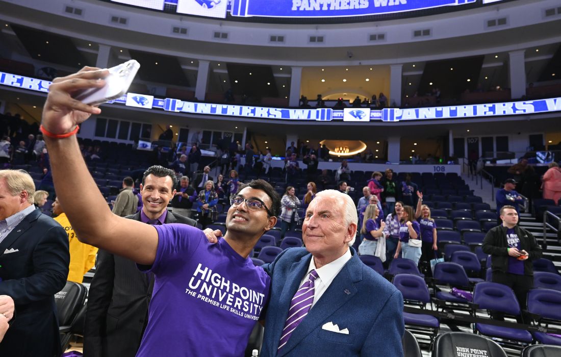 student taking photograph with nido qubein hpu basketball espnu game