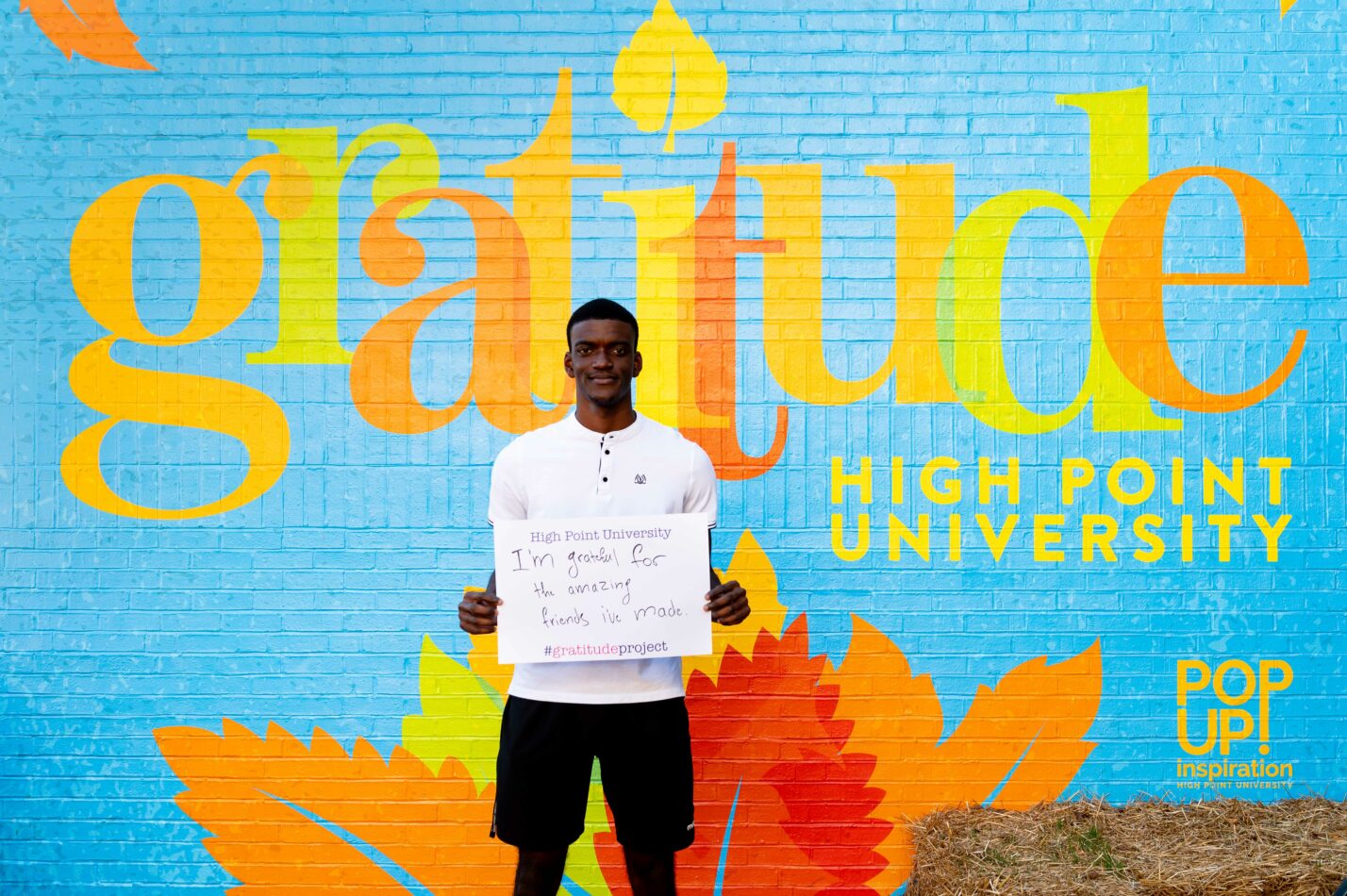 Student holding sign grateful for family and friends at High Point University